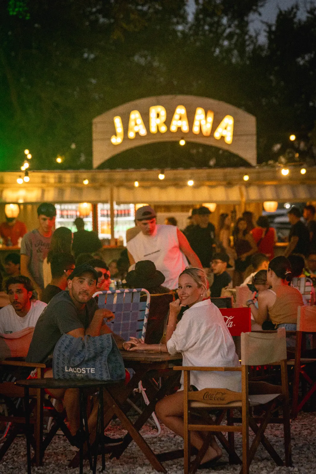 Pareja sentada en una mesa frente al cartel luminoso de Jarana