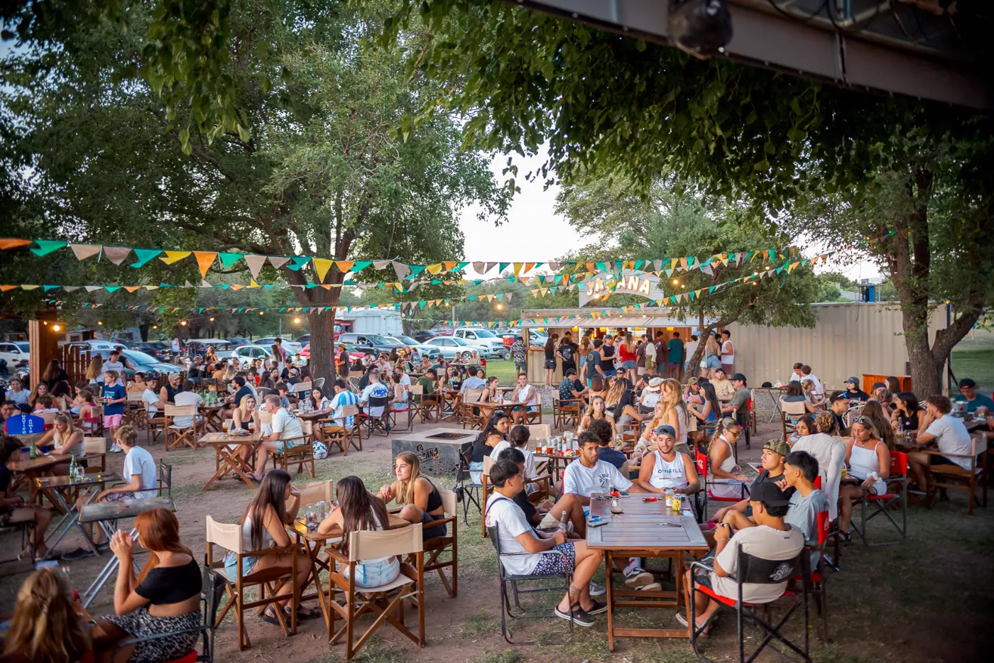 Mesas al aire libre bajo los árboles en Jarana, al atardecer